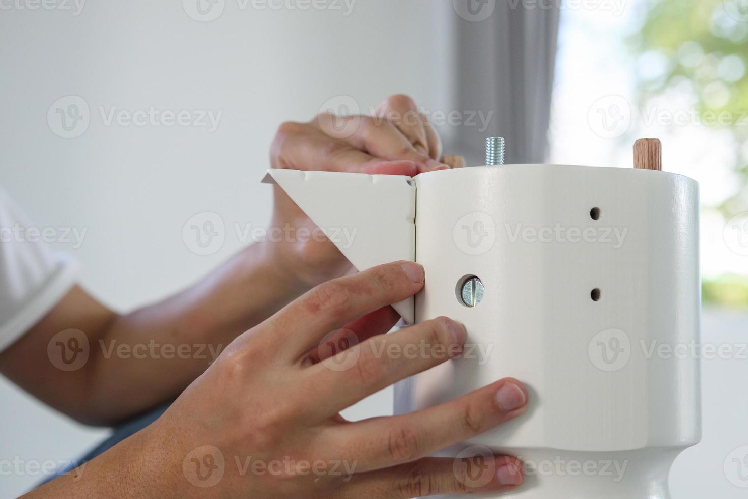 Asian man assembling white table furniture at home photo