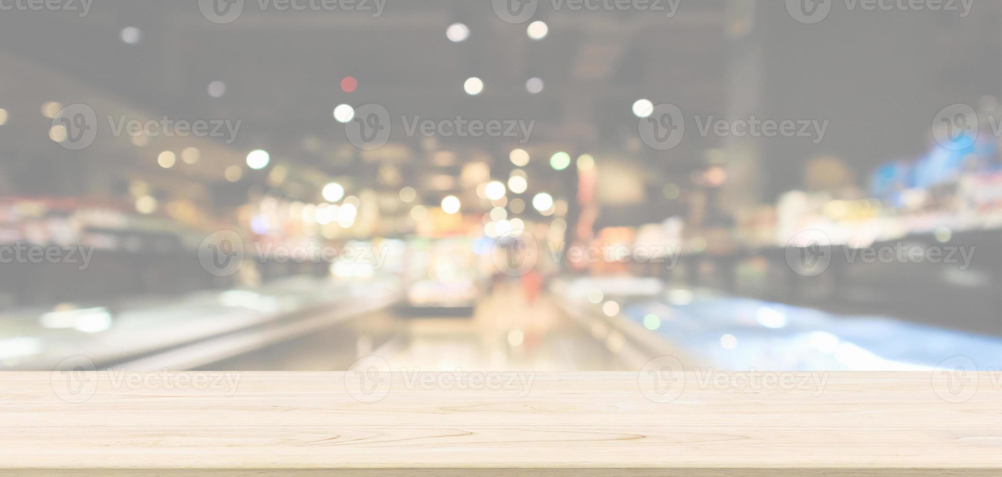 Empty wood table top with abstract supermarket aisle interior blurred defocused background with bokeh light photo
