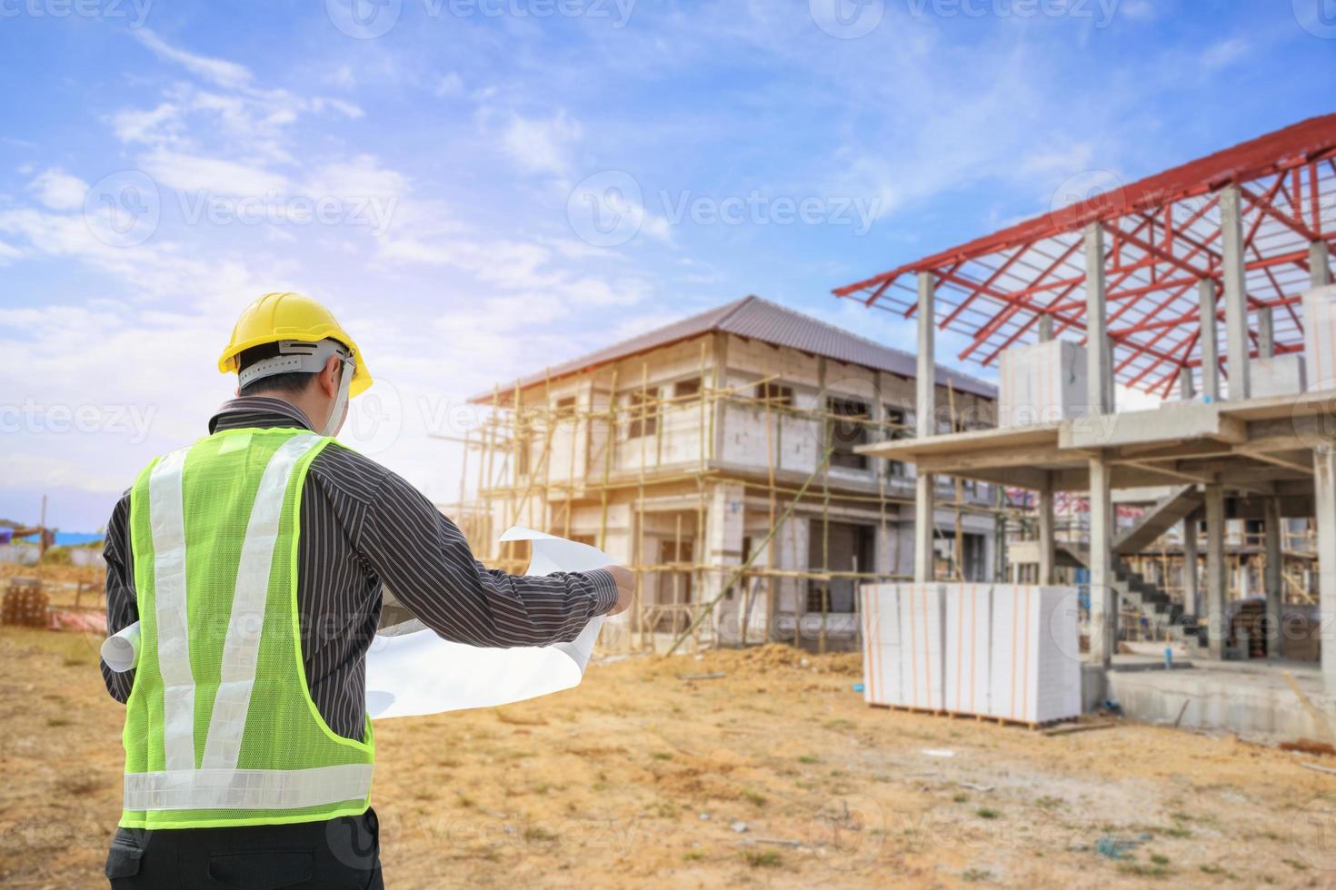 Professional engineer architect worker with protective helmet and blueprints paper at house building construction site photo
