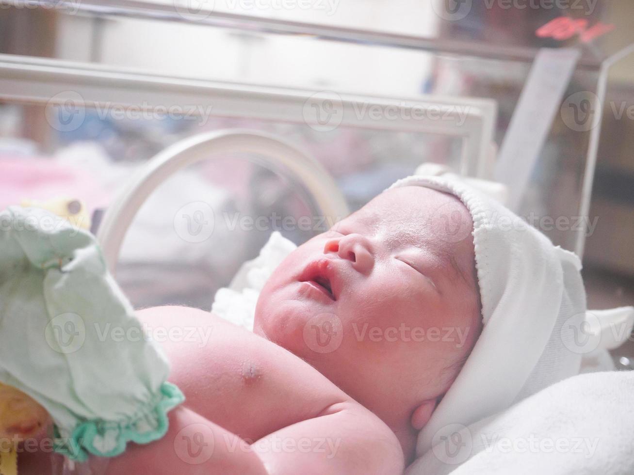 Newborn baby inside incubator in hospital post delivery room photo