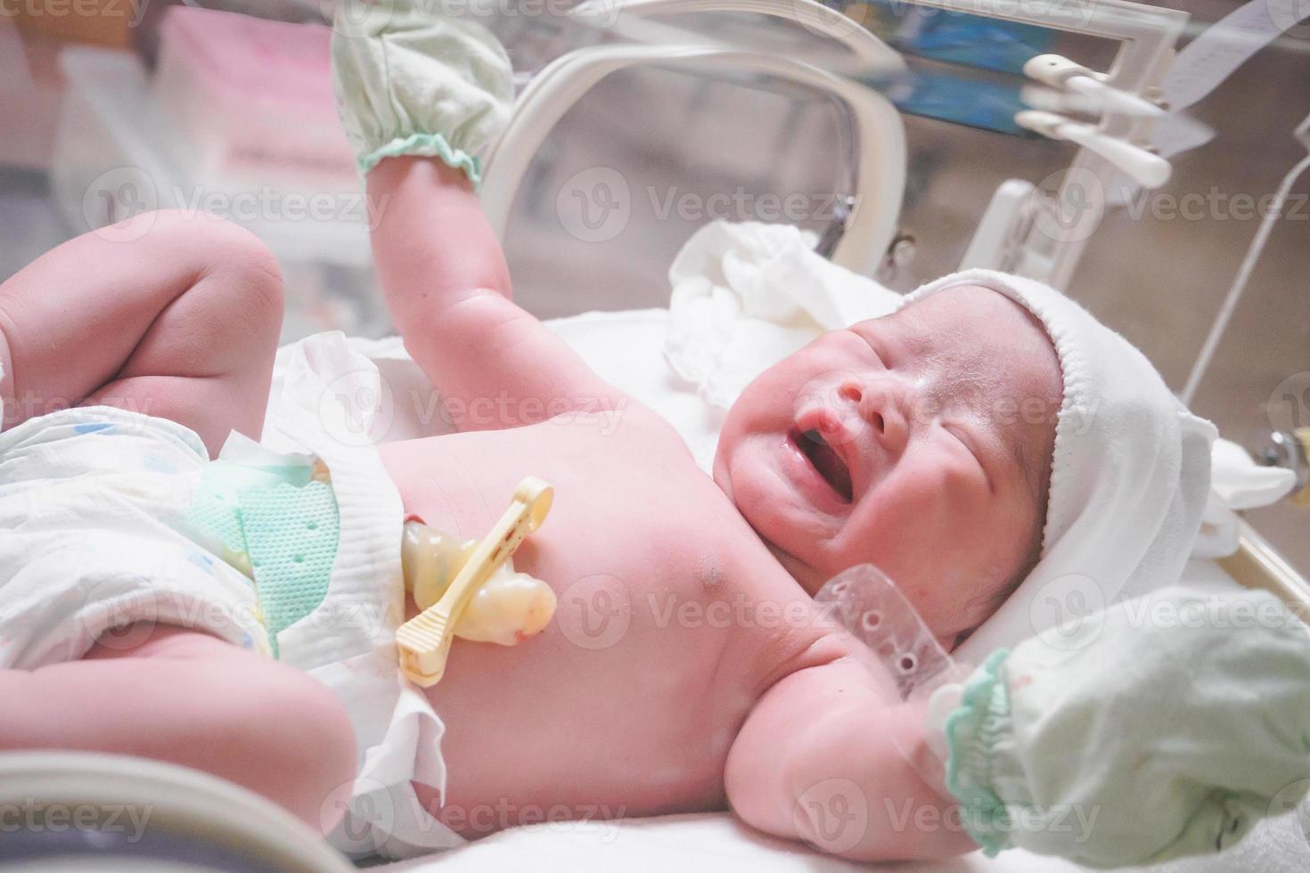 Newborn baby inside incubator in hospital post delivery room photo