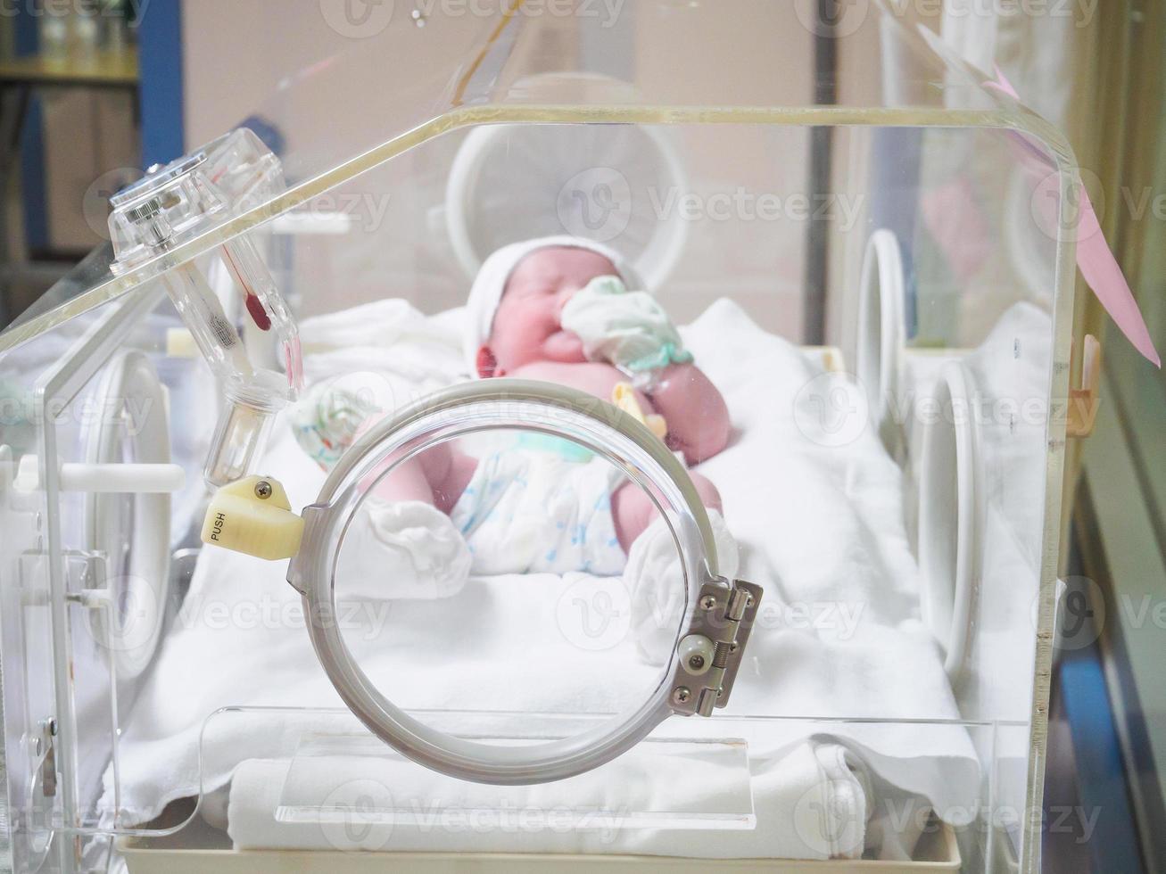 Newborn baby inside incubator in hospital post delivery room photo