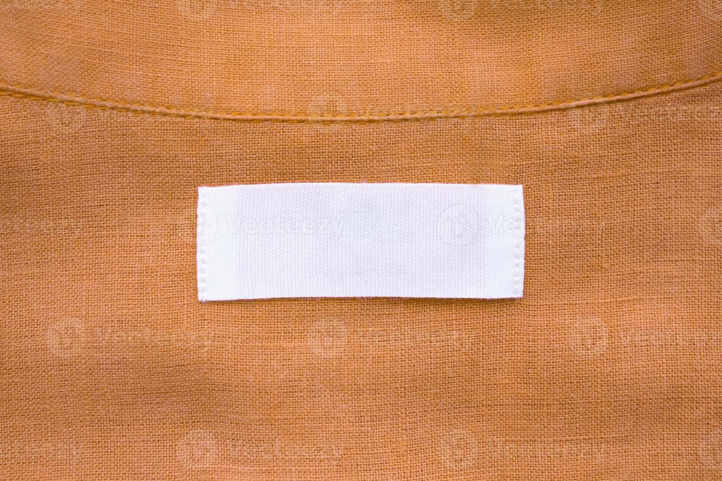 White blank clothing tag label on brown linen shirt fabric texture background photo