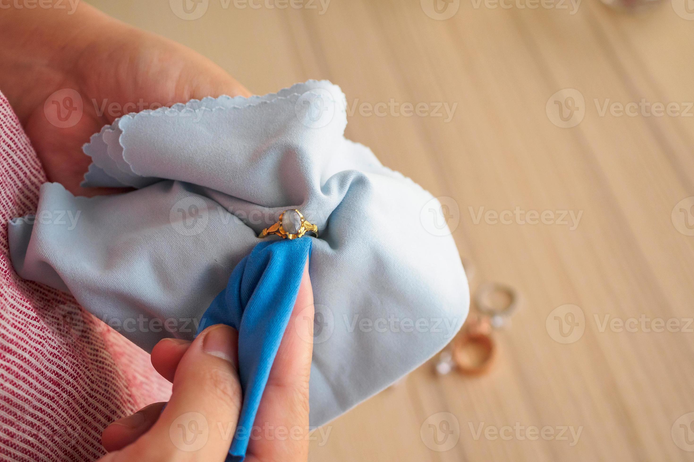 Jeweller hand polishing and cleaning gold jewelry ring with micro fiber