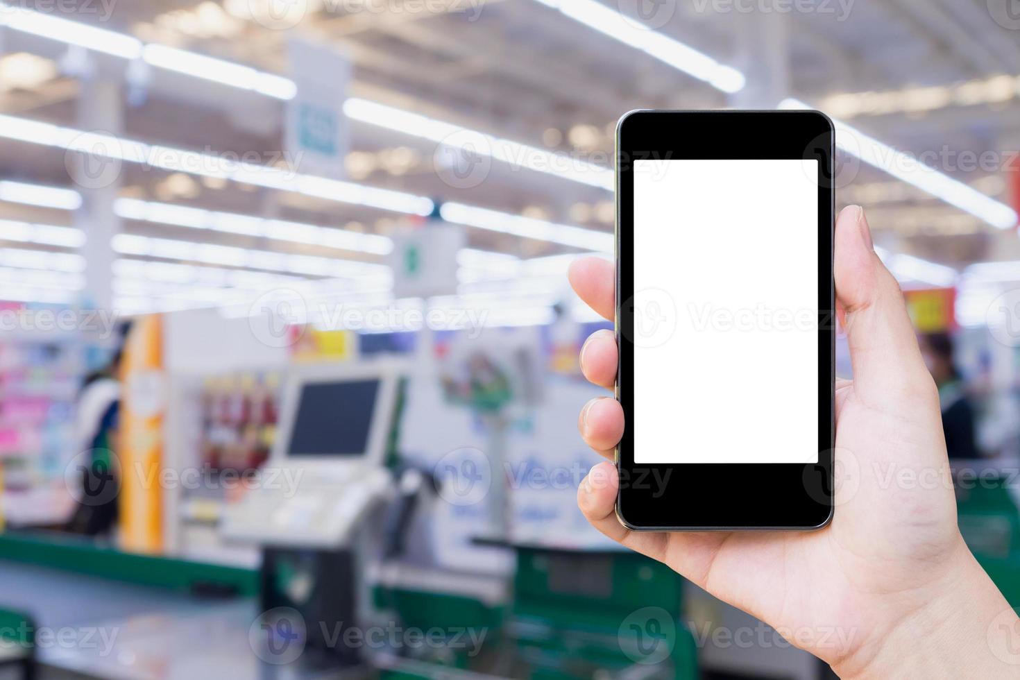 Woman hand holding mobile phone at supermarket checkout background photo