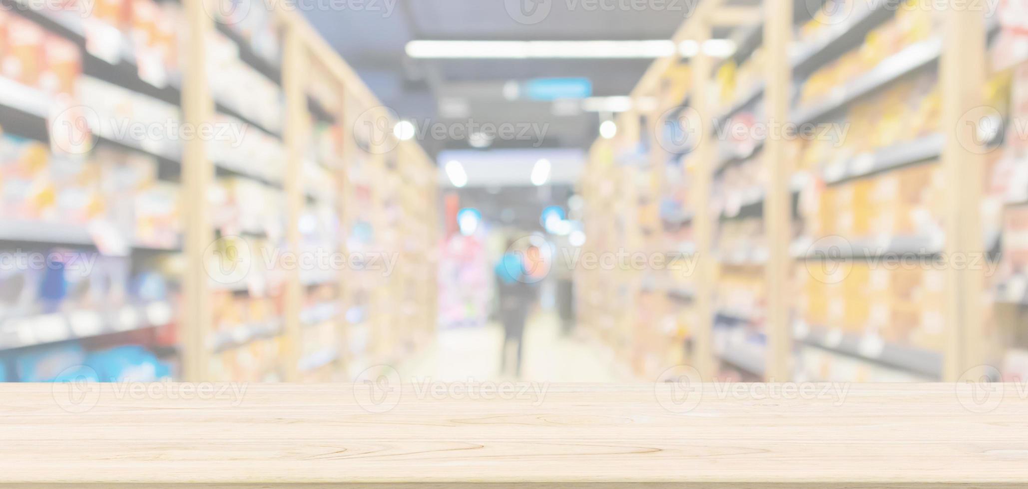 Empty wood table top with supermarket aisle with product shelves interior defocused blur background photo