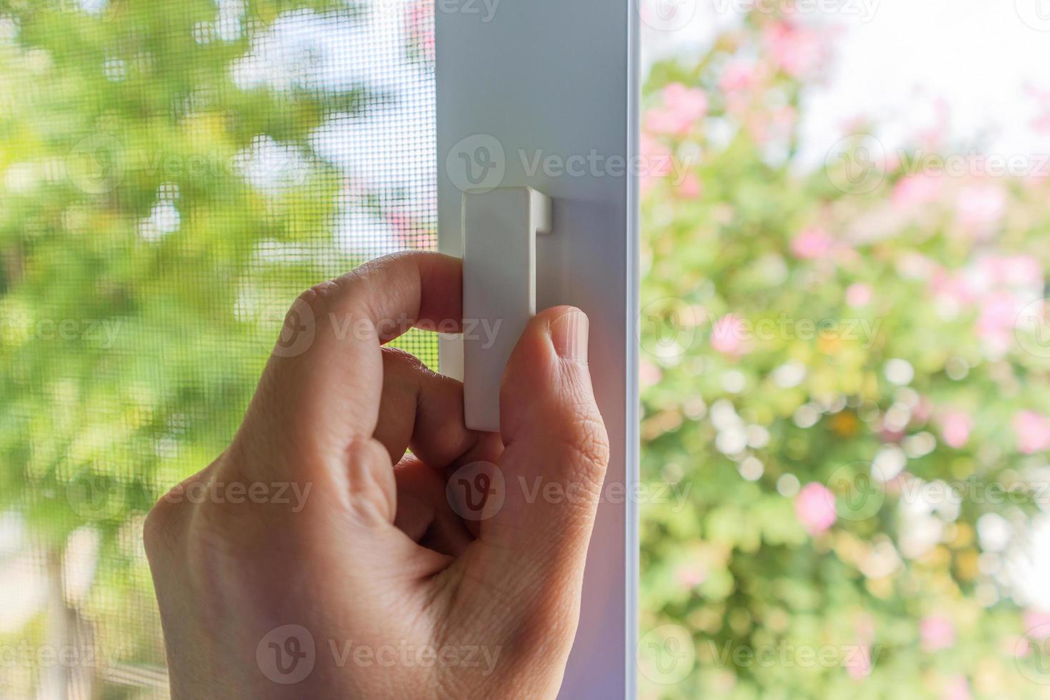 Hand hold mosquito net wire screen handle on house window photo