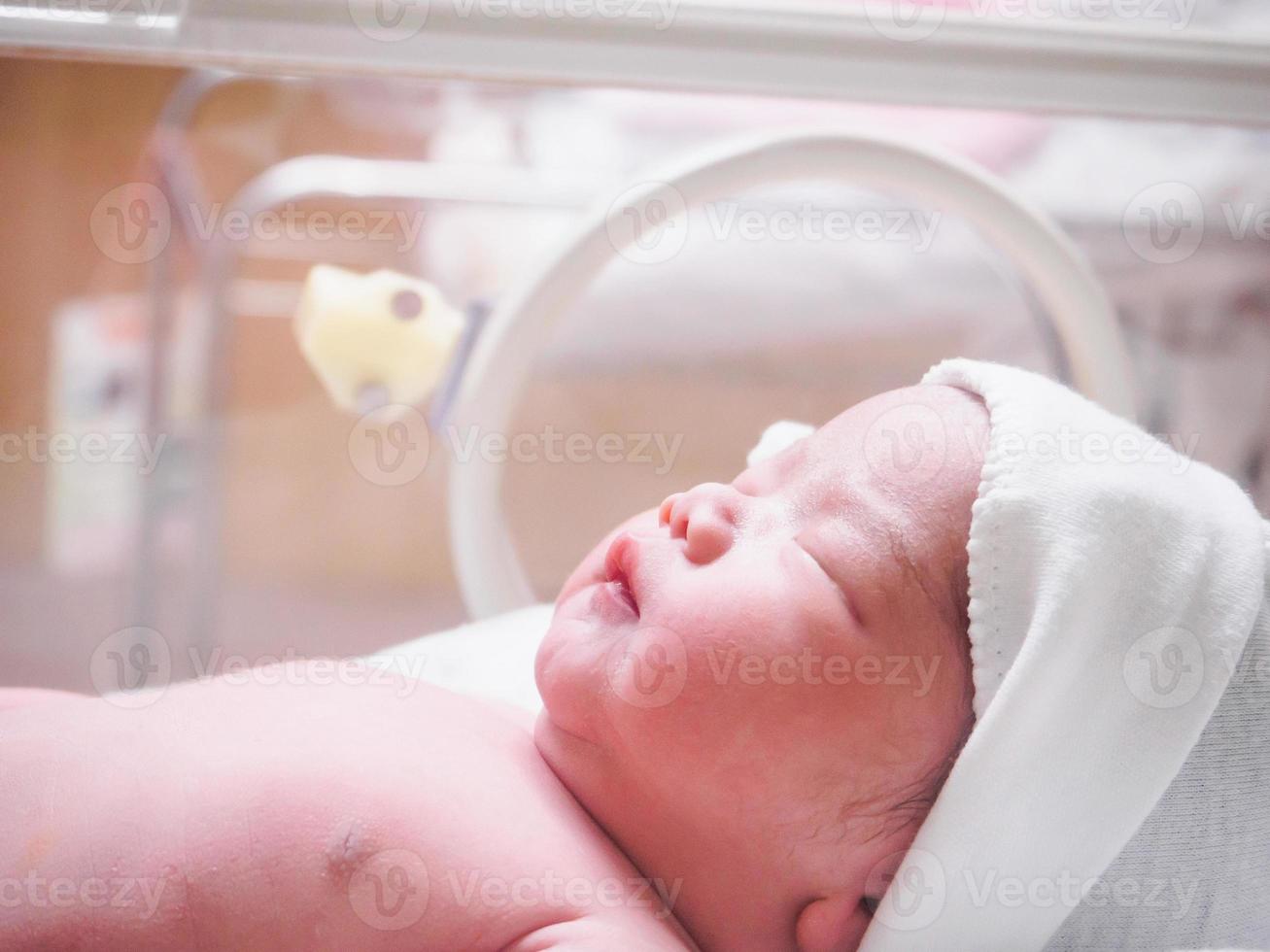 bebé recién nacido dentro de la incubadora en la sala de postparto del hospital foto