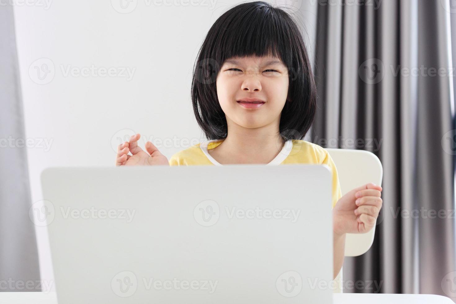 little asian girl student study online using laptop computer at home photo