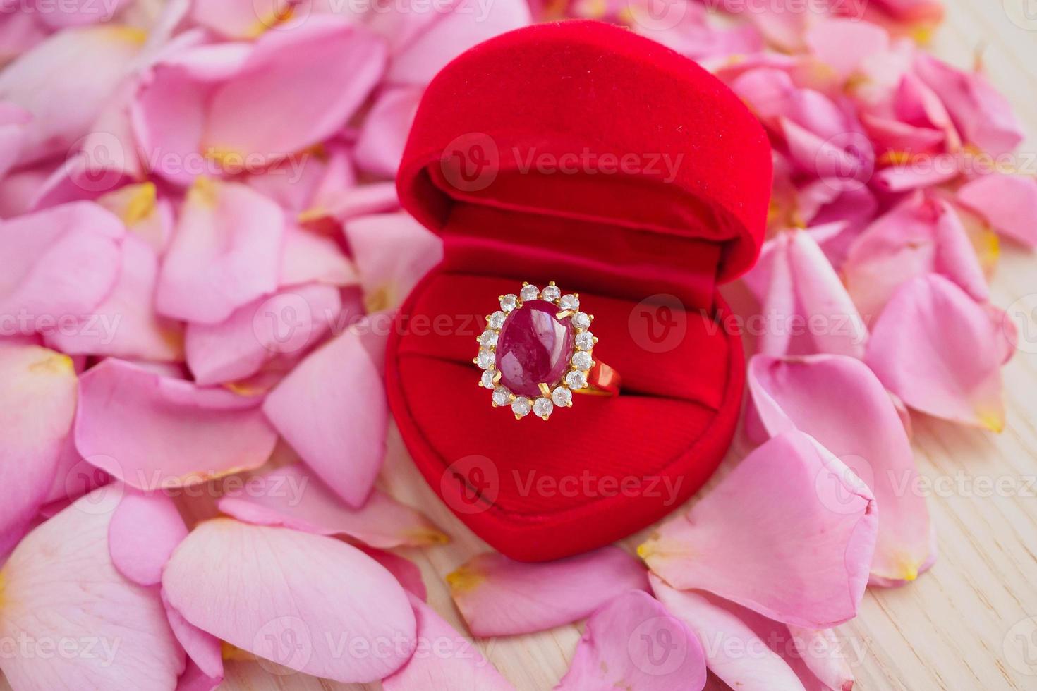elegant ruby ring in red heart jewelry box on beautiful pink rose petal background close up photo