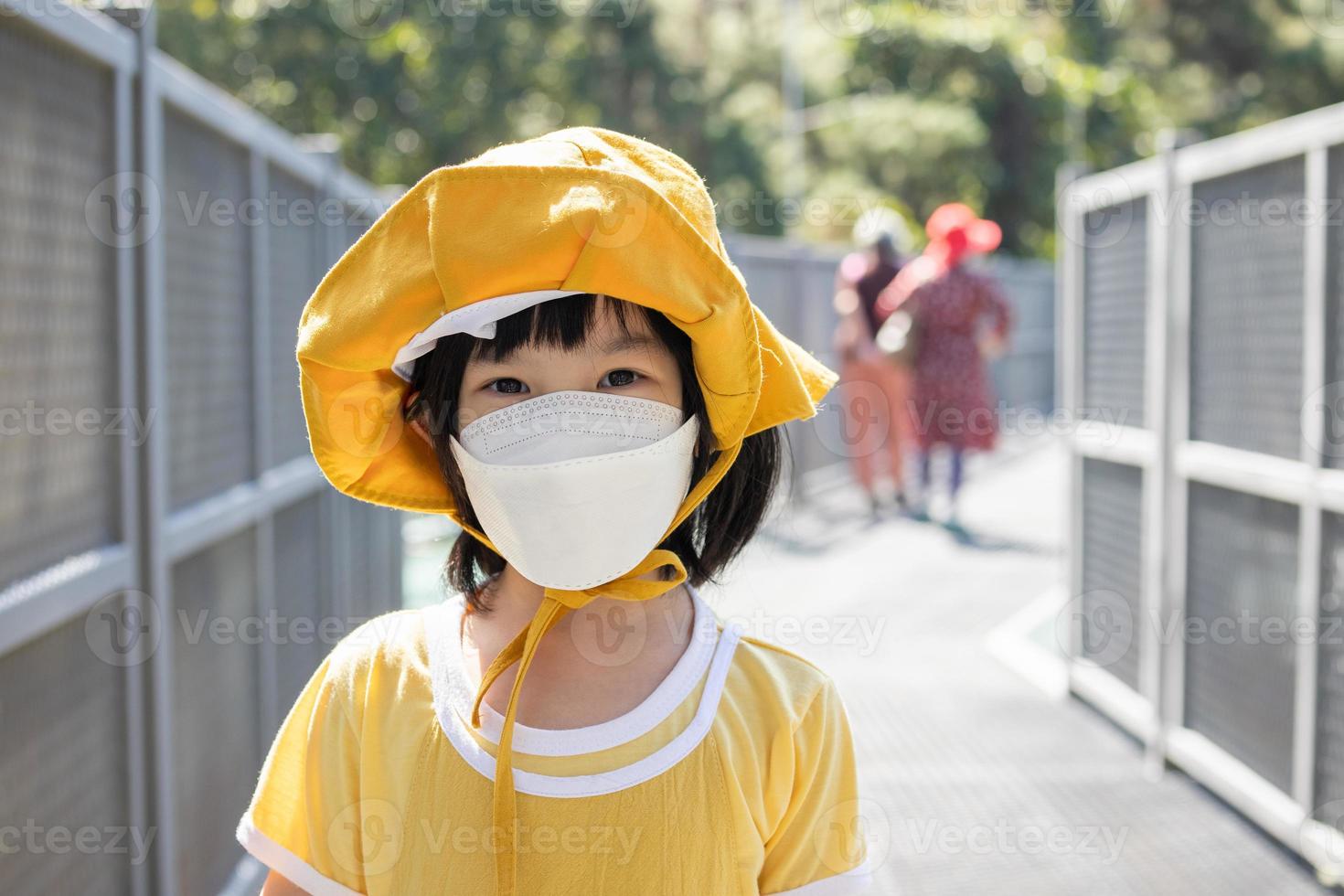 Little asian girl wearing face mask in the park New normal lifestyle travel during covid-19 pandemic photo