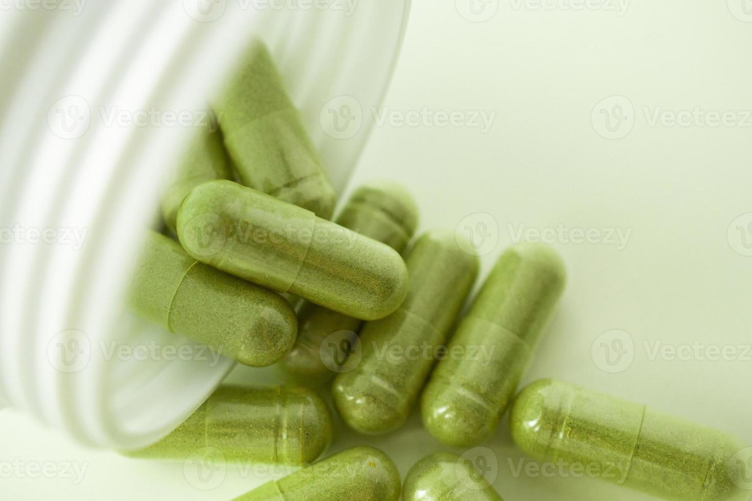 Herbal medicine capsules with bottle on white background photo