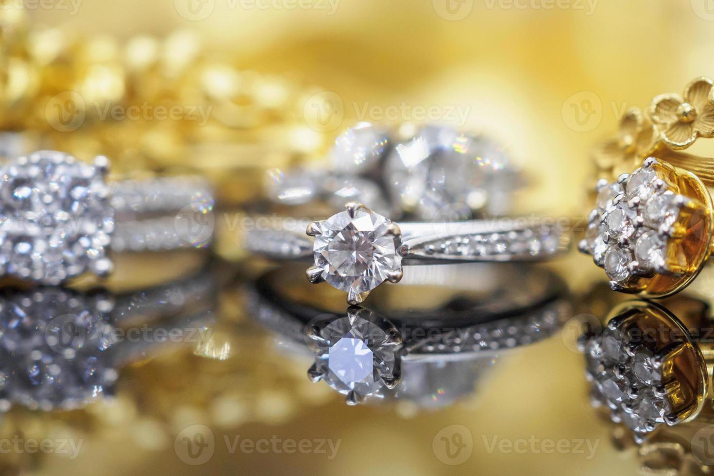 anillos de diamantes de joyería de lujo con reflejo en el fondo negro y dorado foto