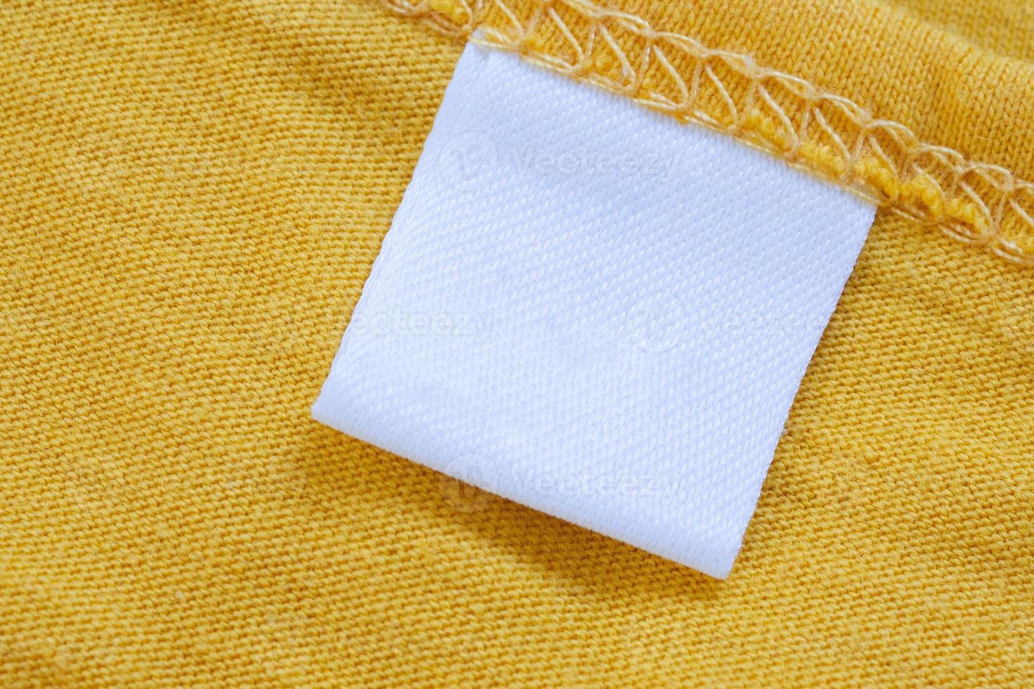White blank clothing tag label on new yellow shirt background 12810489
