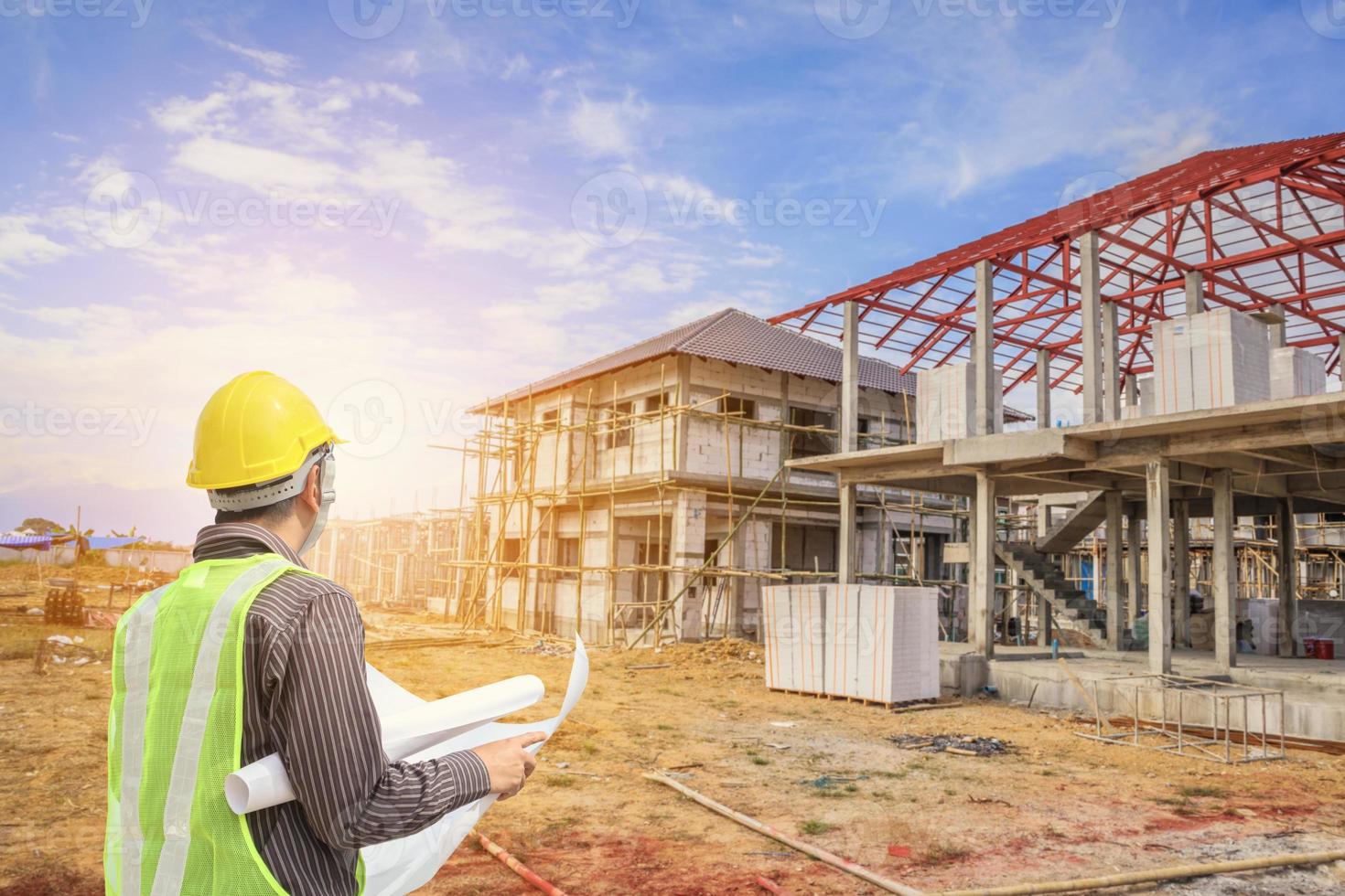 Professional engineer architect worker with protective helmet and blueprints paper at house building construction site photo