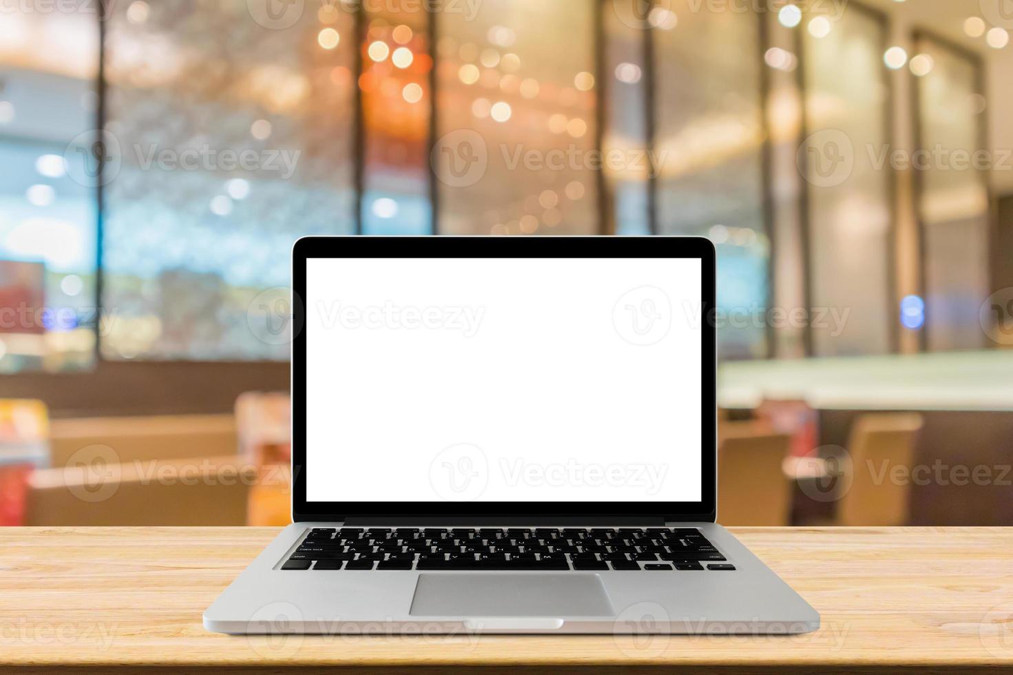 Blank screen laptop computer on wood table top with blur cafe restaurant with abstract bokeh light defocused background photo