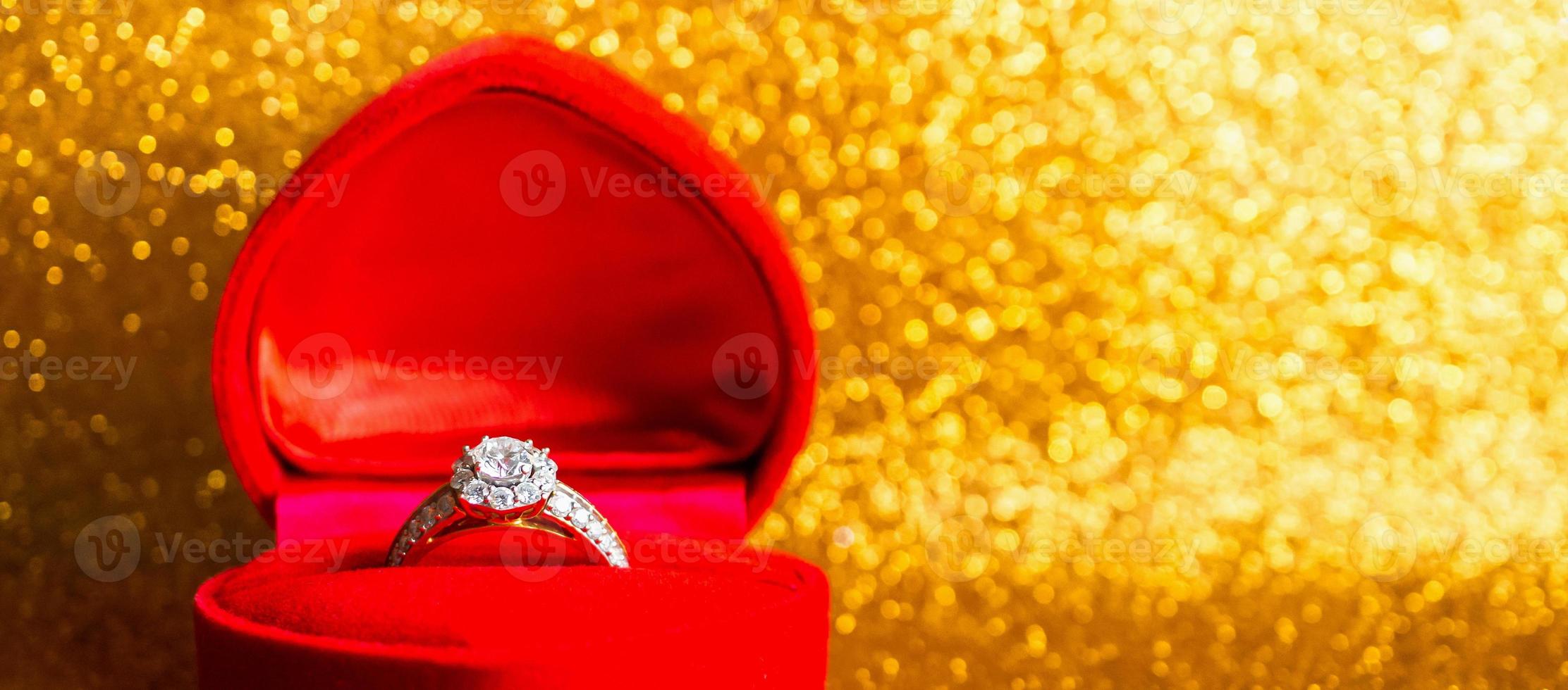 Jewelry diamond ring in gift box with abstract festive glitter Christmas holiday texture background blur with bokeh light photo