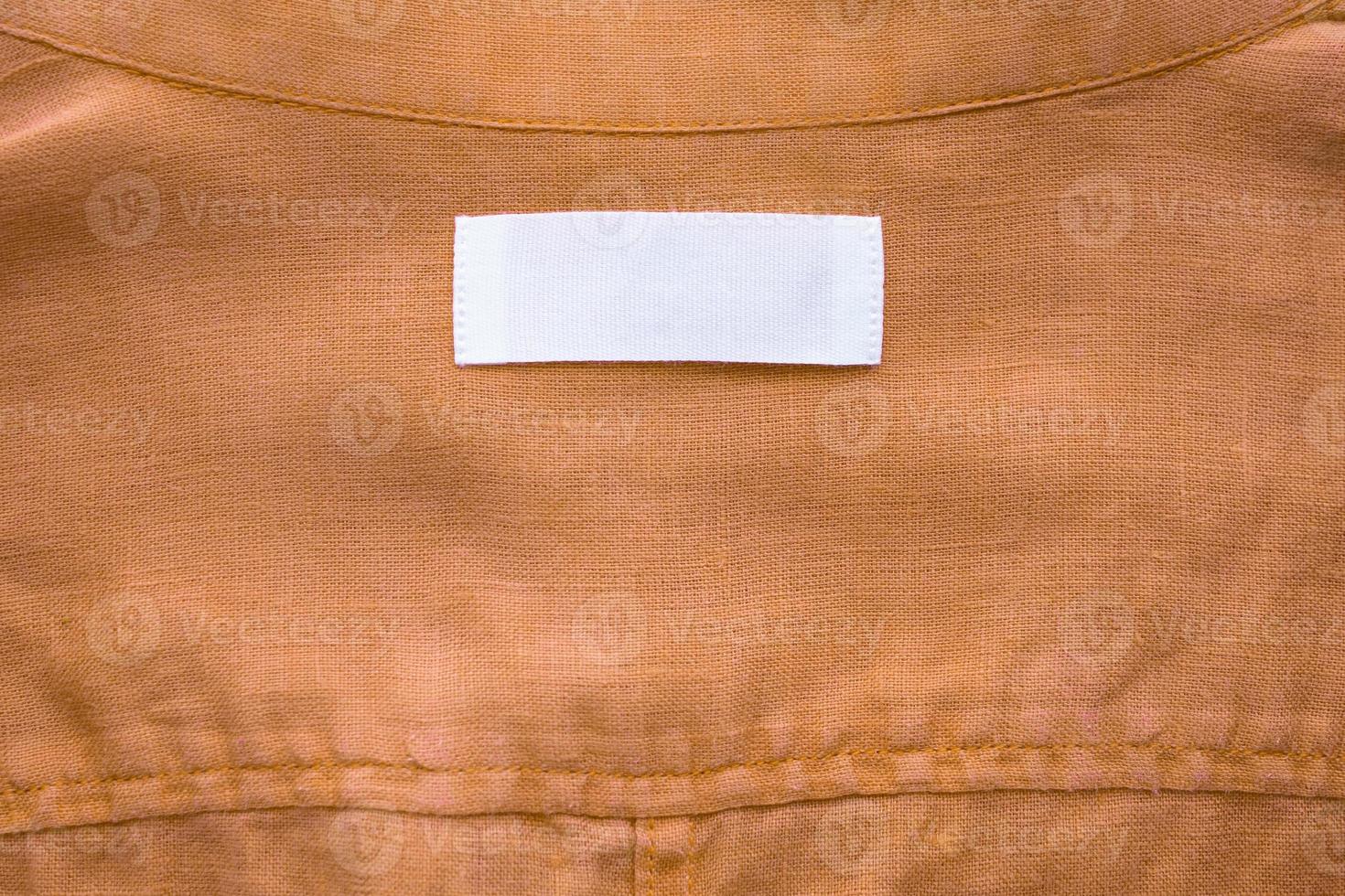 White blank clothing tag label on brown linen shirt fabric texture background photo