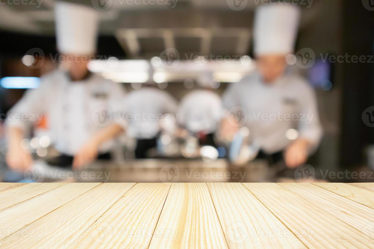 Empty Wood table top with Chef cooking in restaurant kitchen blurred