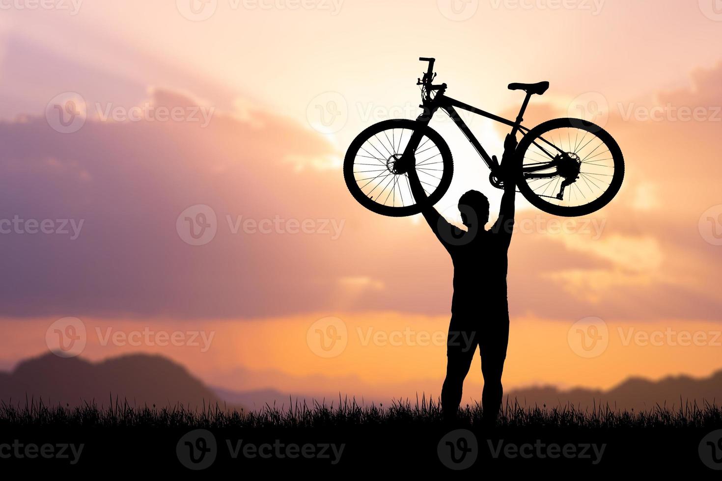 Man holds a bicycle on top of a mountain. concept of success and victory photo