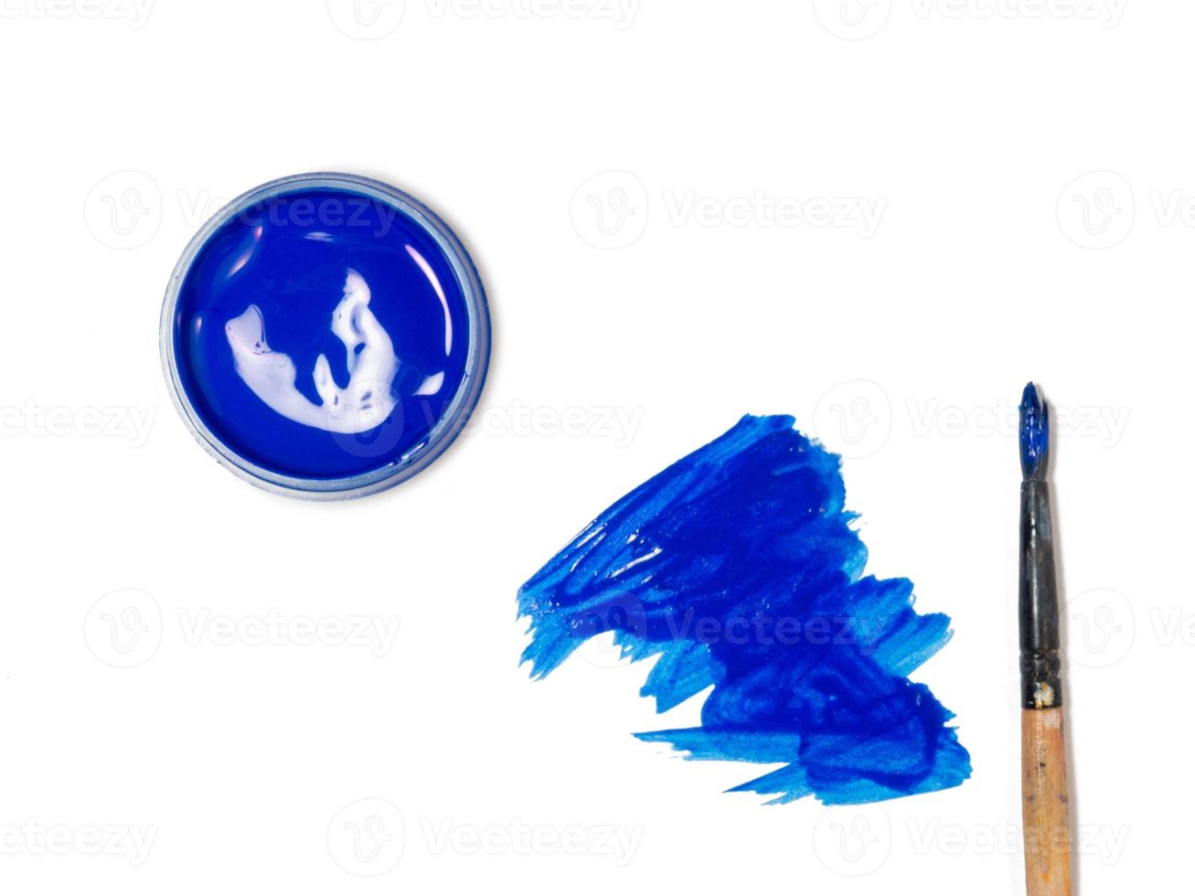 blue acrylic in a jar. drops of paint on the table. photo