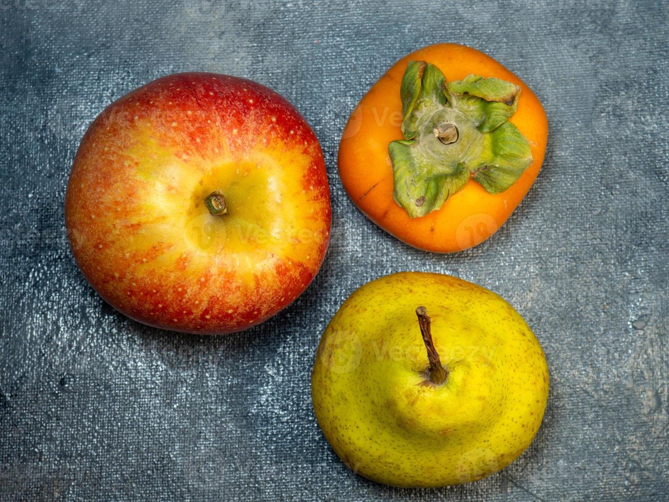 apple, persimmon and pear on a black background. Persimmon Chamomile. Apple Gala. Pear lucas. Still life of fruits photo
