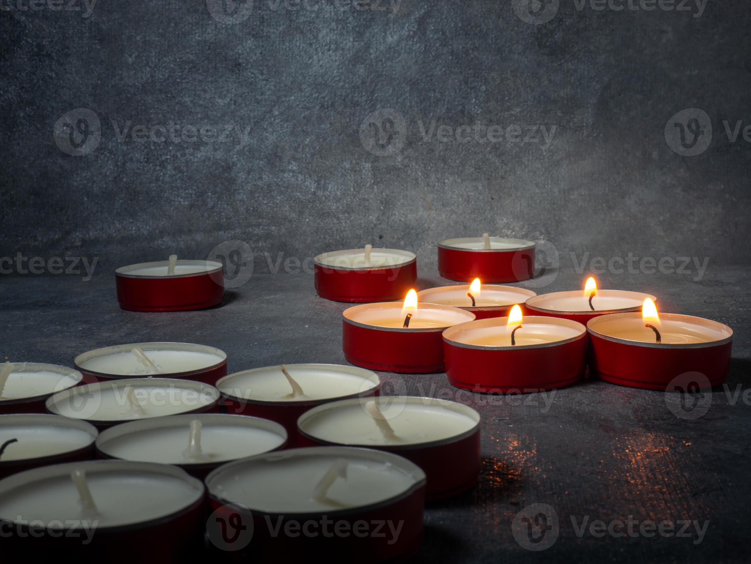 Short candles are burning against a dark background. Lots of small