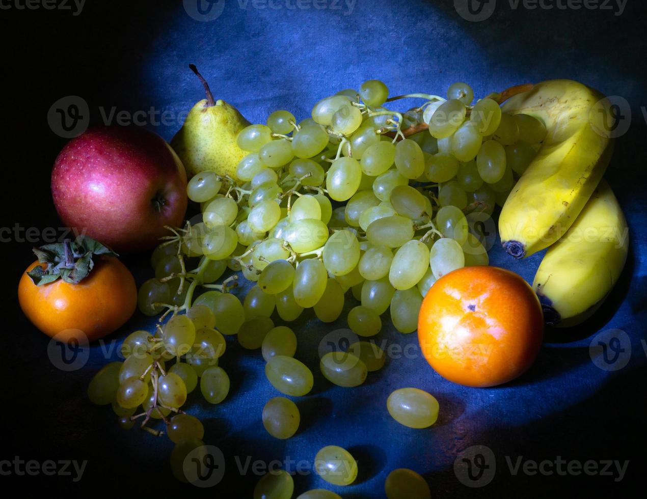 Still life of fruits. apple, persimmon, pear and grapes on a black background.  Persimmon Chamomile. Apple Gala. Pear Lucas. Healthy eating. photo