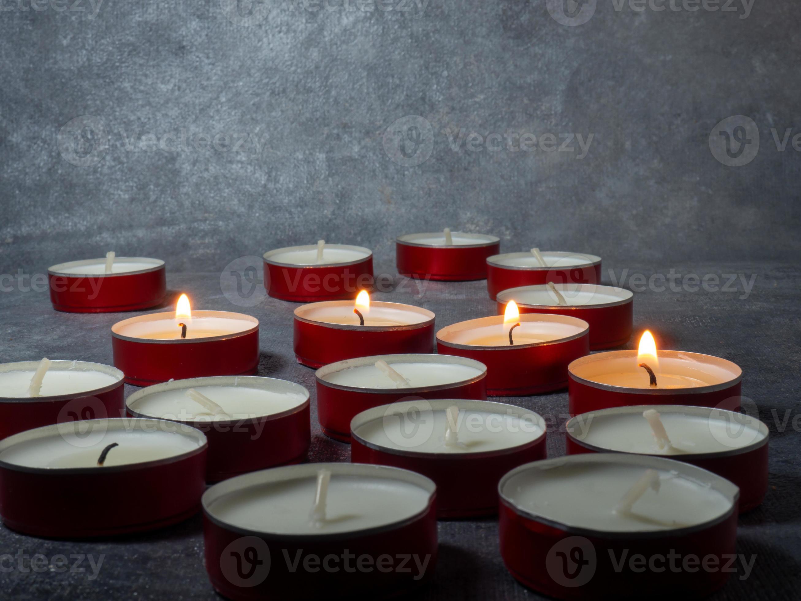 Short candles are burning against a dark background. Lots of small