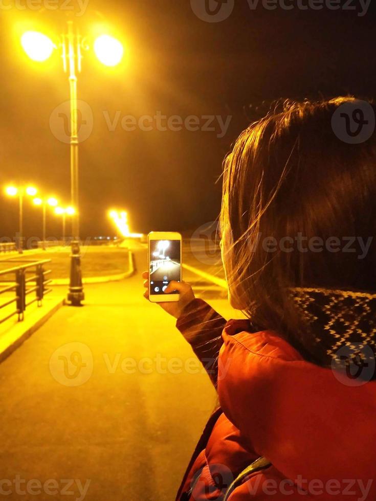 mujer joven tomando fotos al aire libre en el frío día de la tarde