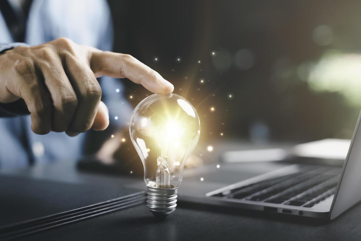Businessman's hand touching on a light bulb, innovative and