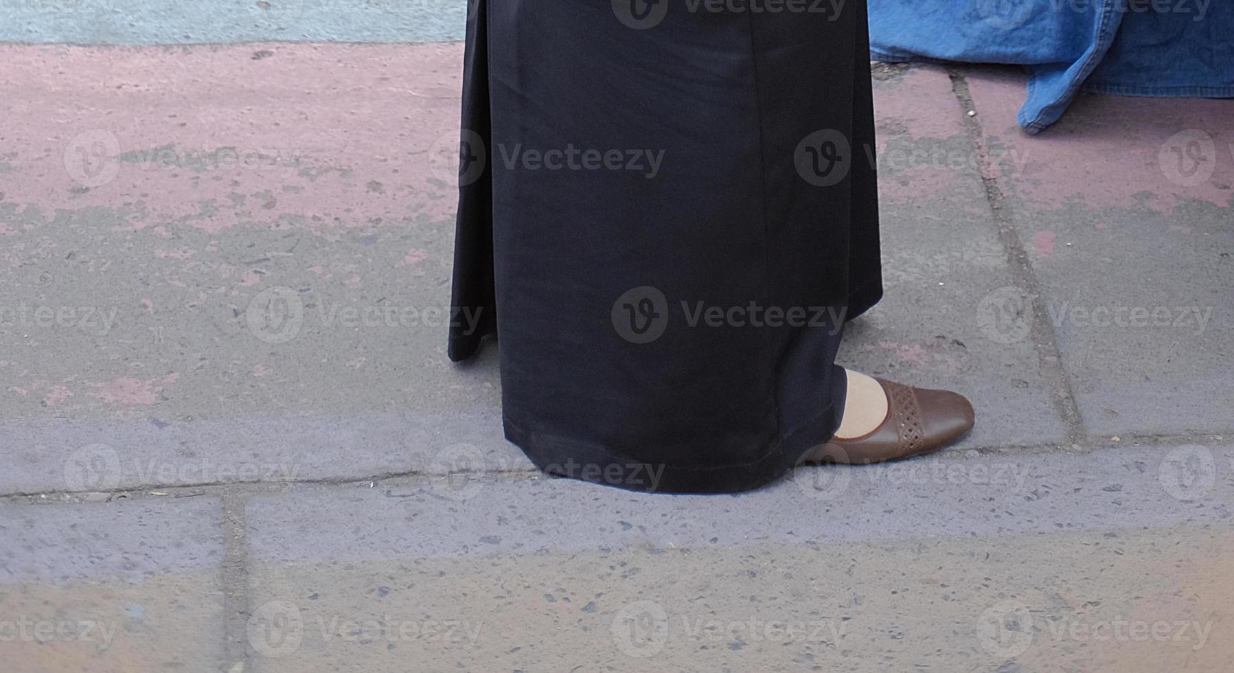 Close up of woman's feet walking. Woman in long skirt and black shoes walking photo