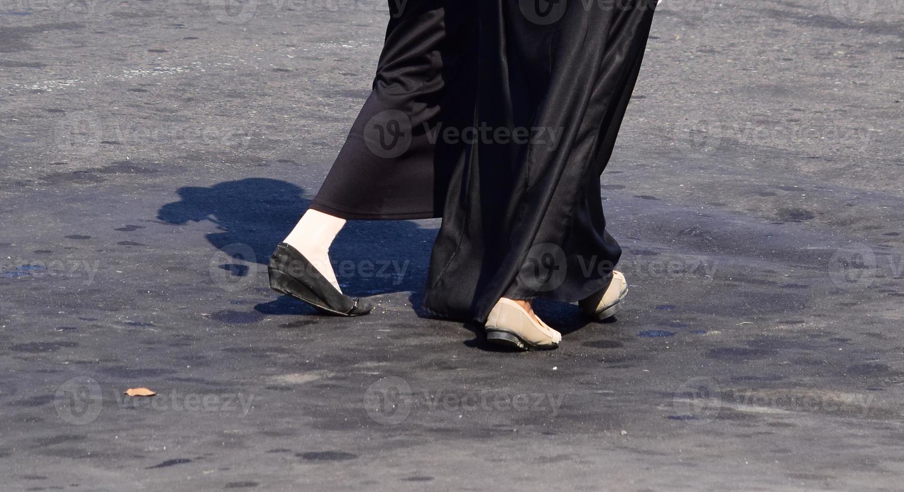 Close up of woman's feet walking. Woman in long skirt and black shoes walking photo