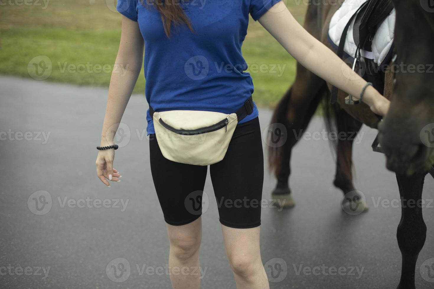 Girl holding horse. Belt bag. Blue t-shirt. Holding horse. photo