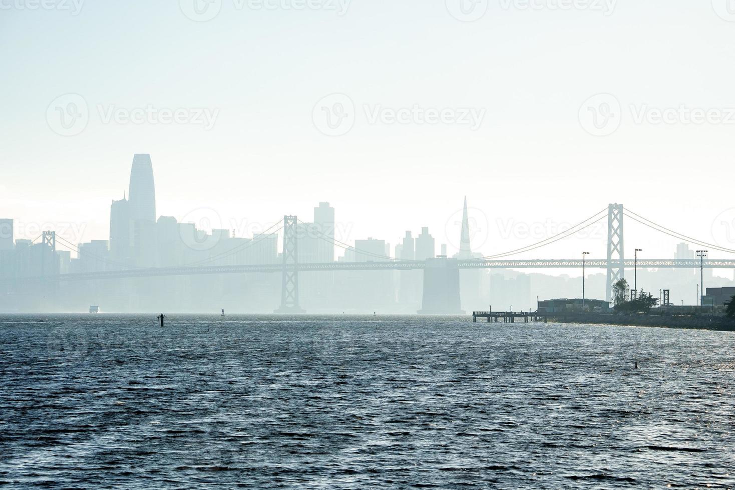 Scenic view of Bay Bridge and city skyline with clear sky in background photo