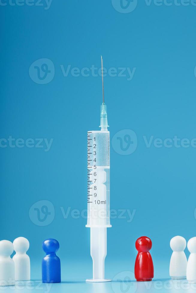 A syringe with a vaccine in the center with a blue and red man with a crowd of whites on a blue background. photo