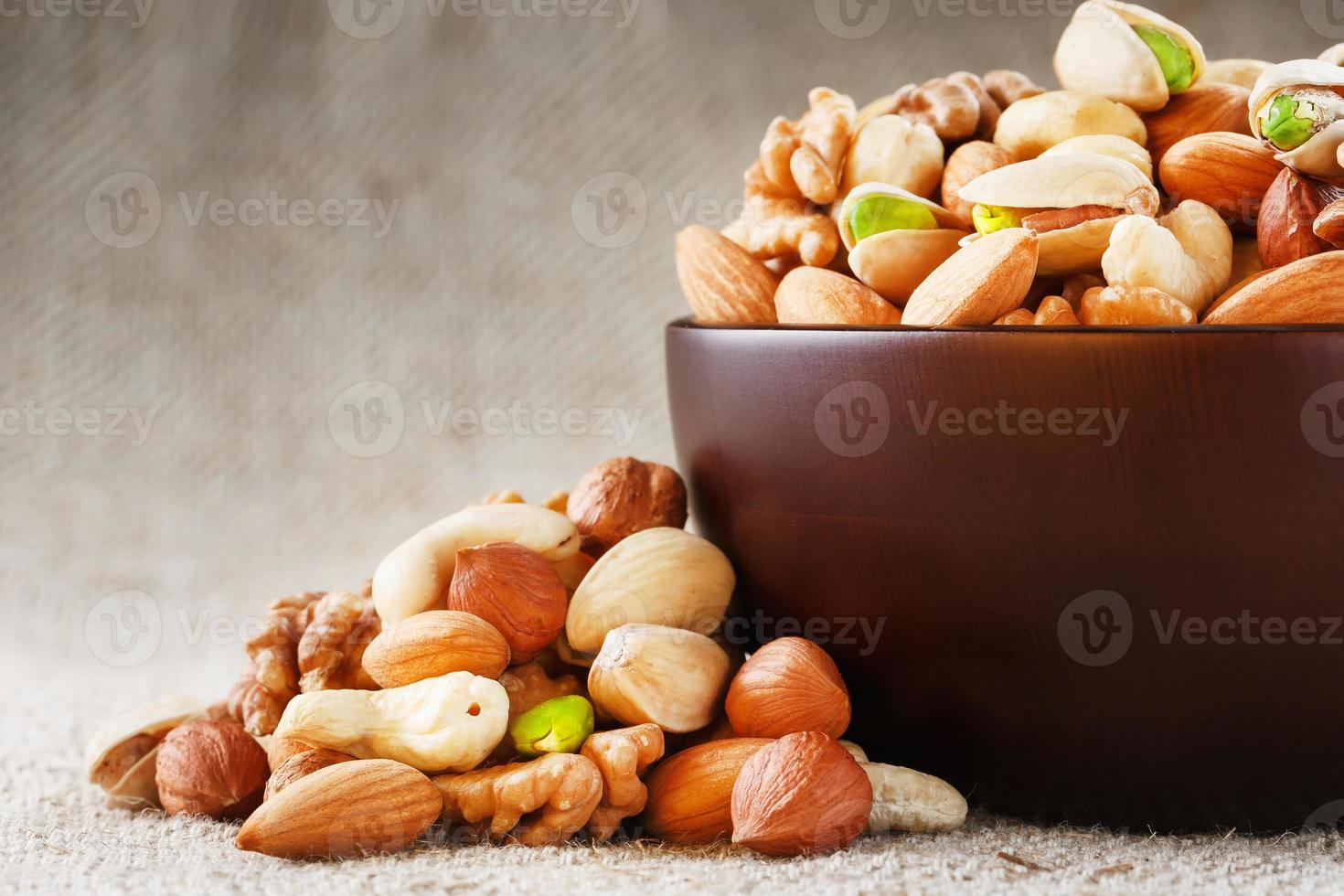 nueces variadas en un plato sobre una mesa de madera con un paño de arpillera. foto