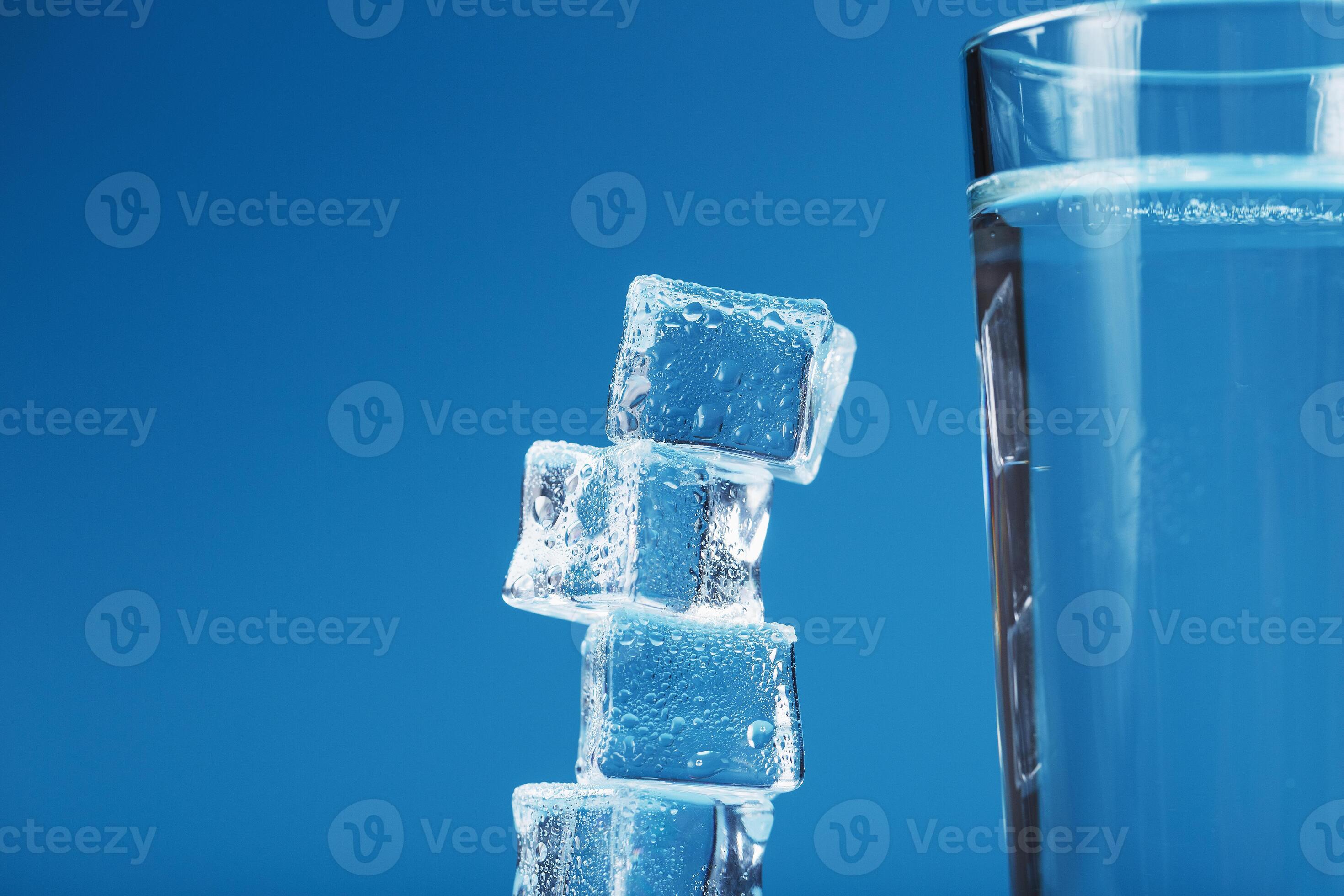 A glass of ice and clear water, ice cubes on a blue background