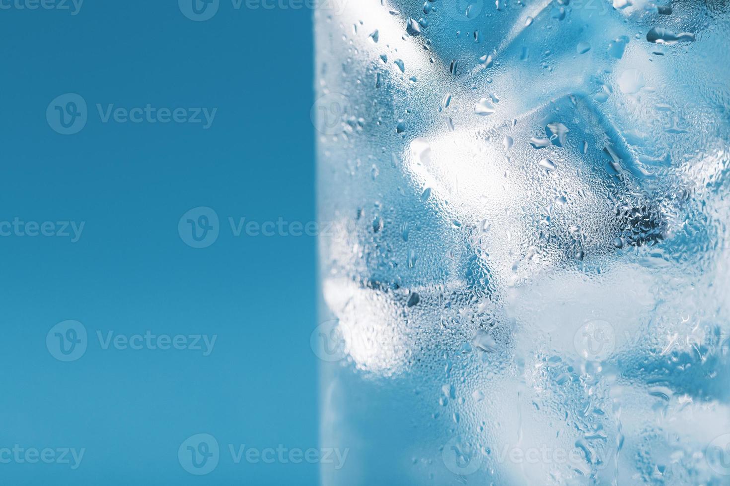 cubos de hielo en un vaso empañado con gotas de macro de primer plano de agua helada. enfoque selectivo suave foto