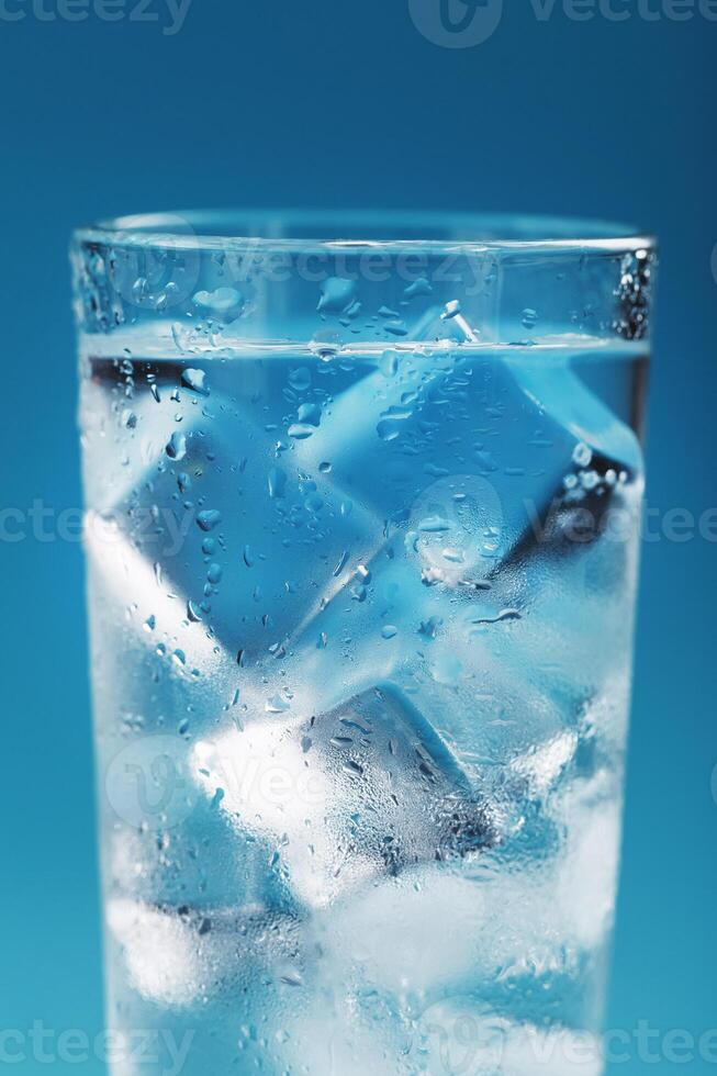 Ice cubes in a glass with refreshing ice water on a blue background