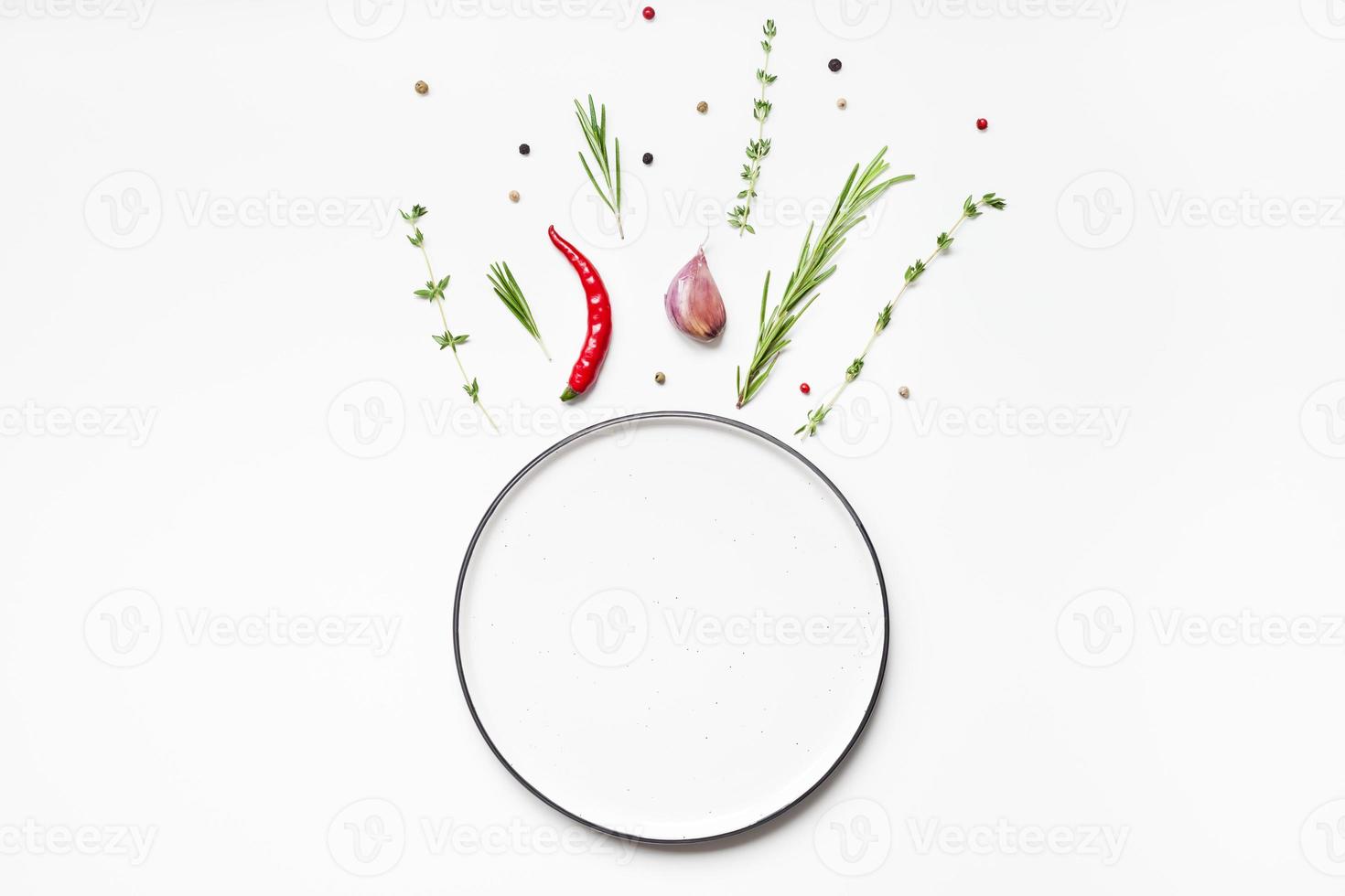 Empty plate with greens herbs and spices around photo