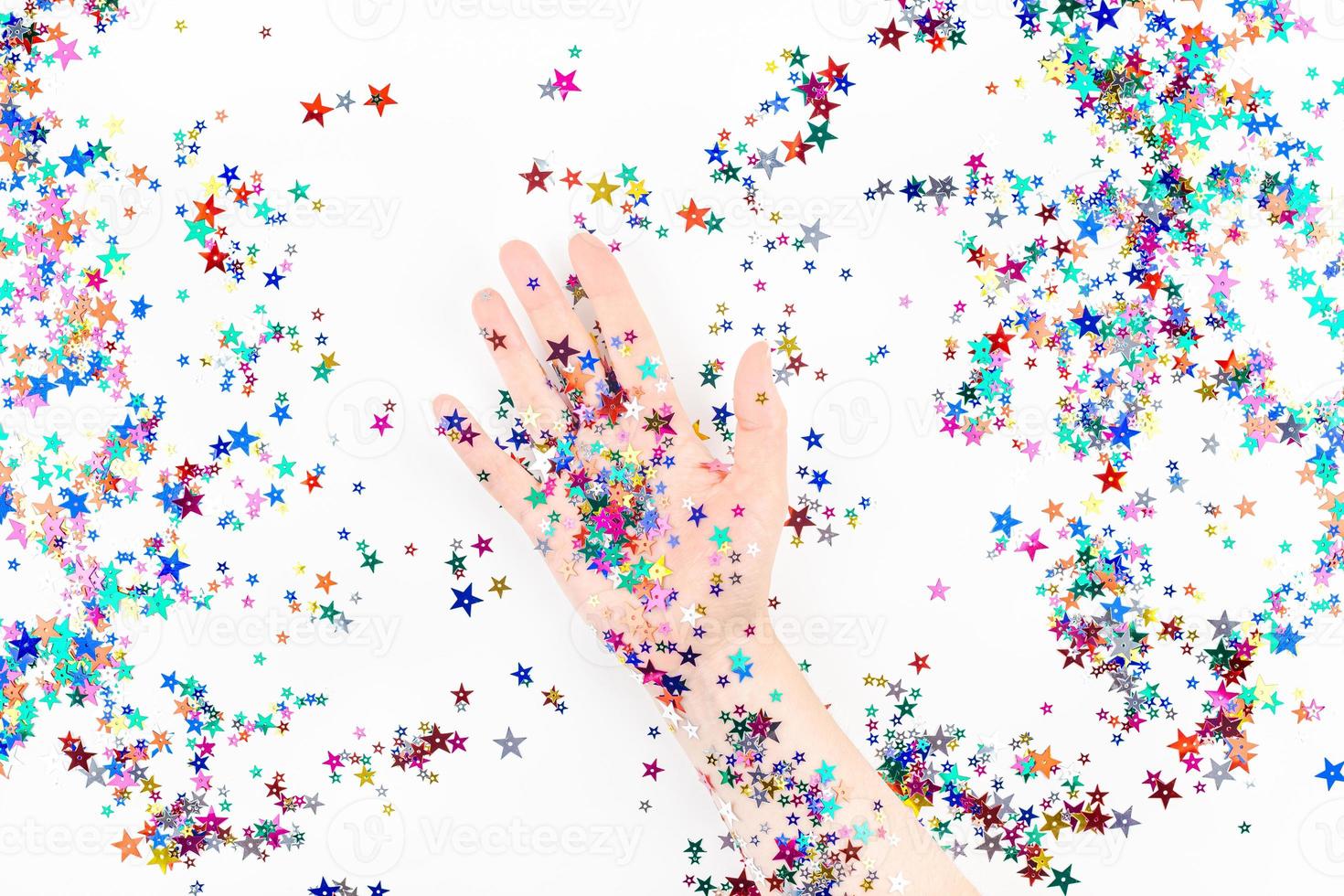 mano de mujer con confeti de estrellas de colores festivos foto