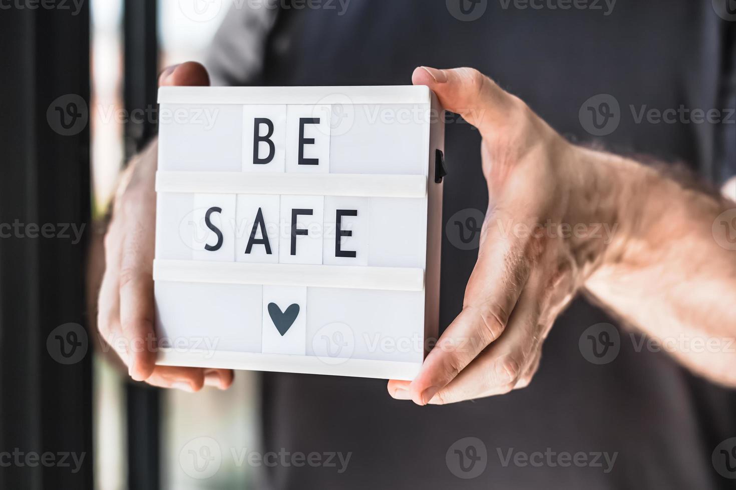 Man holding lightbox with text Be safe in his hand photo