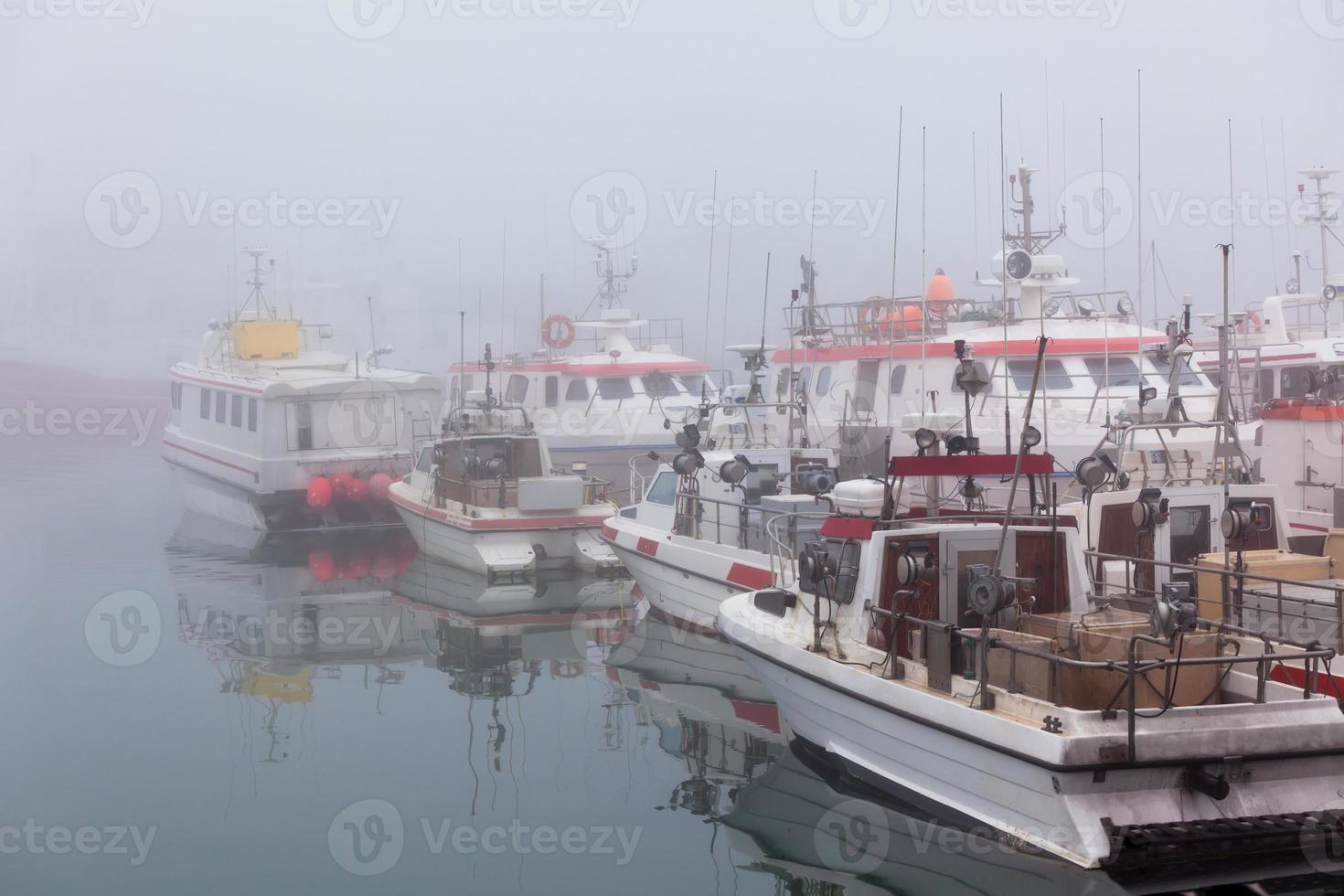 Fishing vessels in a foggy misty morning in Hofn, Iceland photo