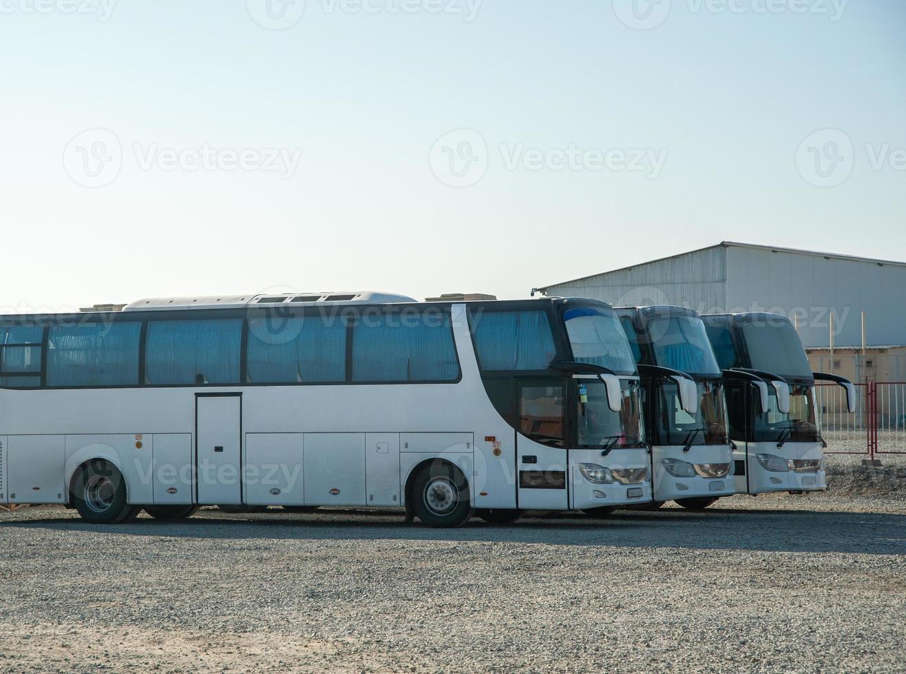 A passenger shift buses stand in a row on a construction site photo