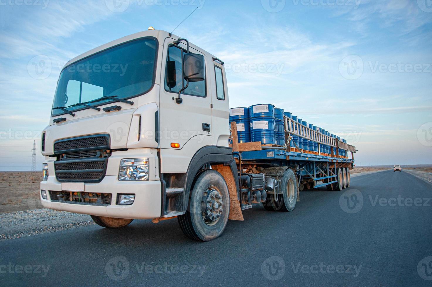A dump truck with metal barrels on the road against a beautiful sky photo