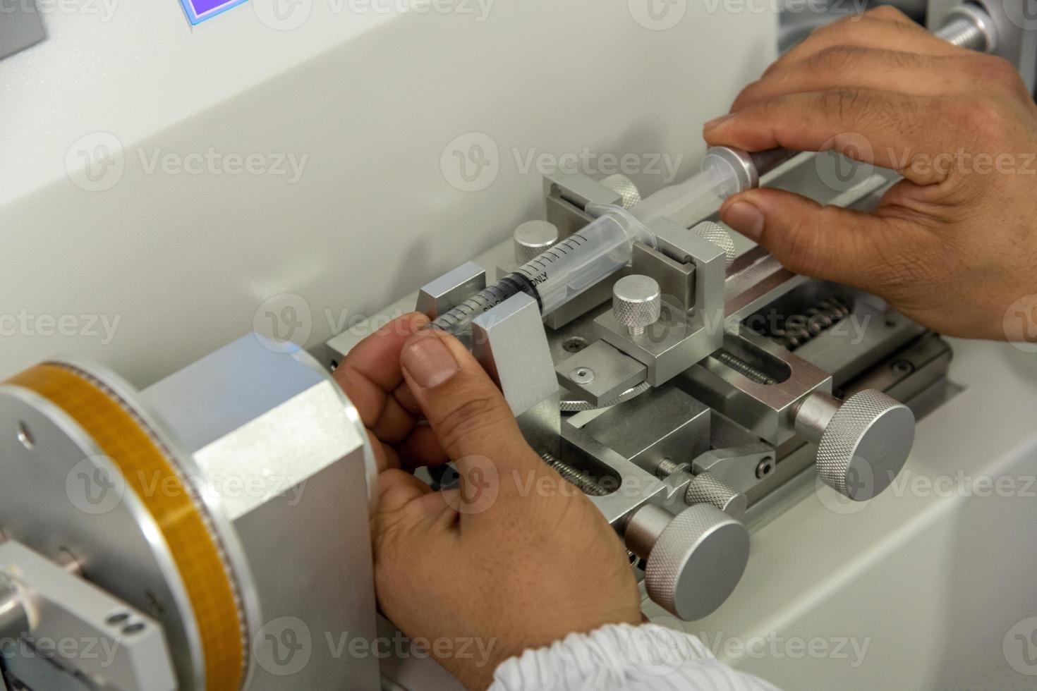 A closeup shot of hands working on a machine in a medical production warehouse for syringes photo