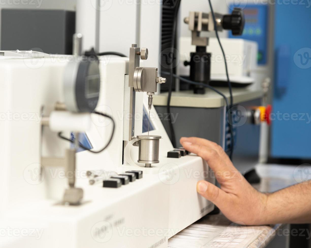 A closeup shot of a hand using a medical machine to test and manufacture pharmaceutical syringes photo