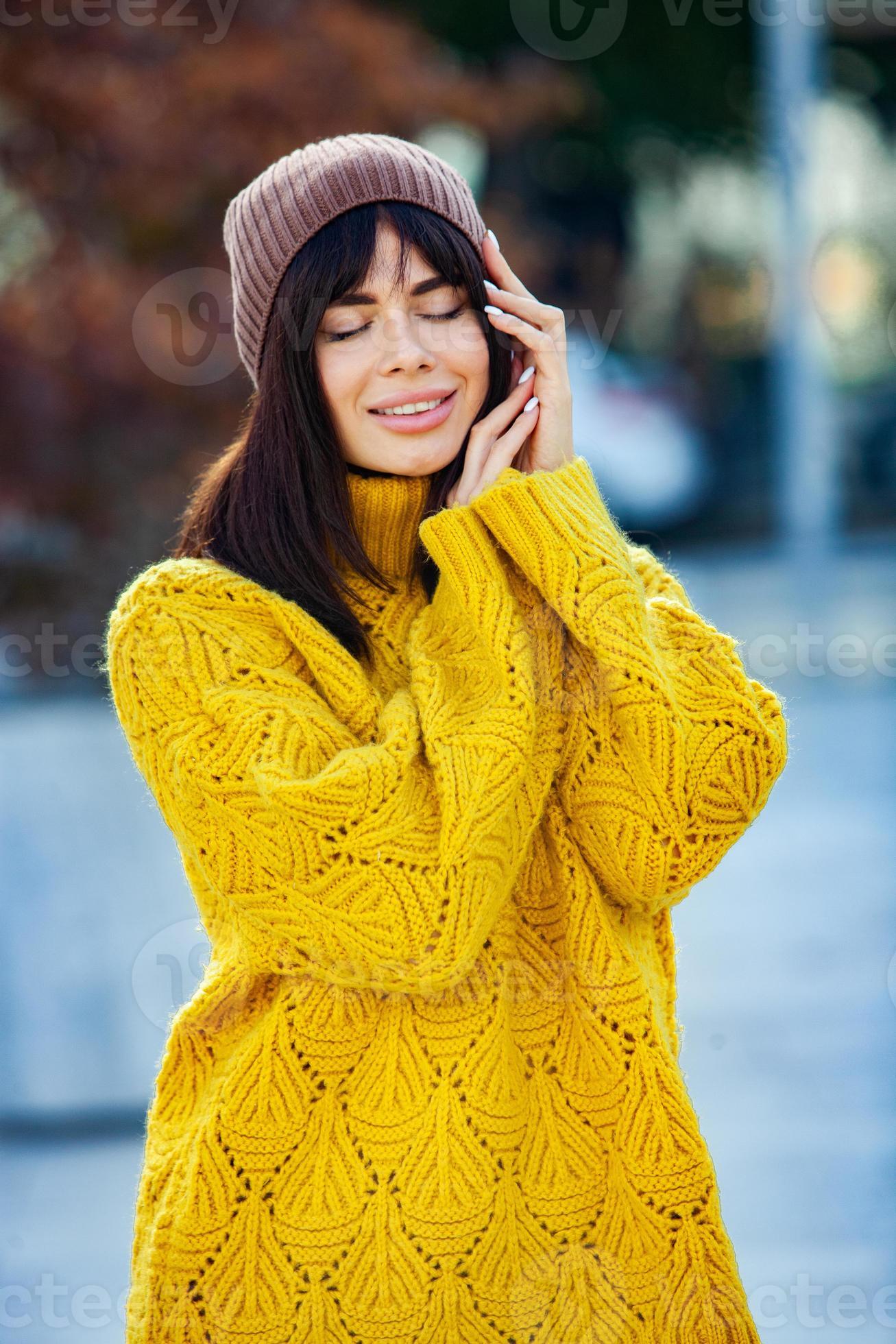 Beautiful European brunette dressed in a yellow woolen sweater and hat  outside. The beautiful girl who wears thick stylish autumn clothes in cool  weather. 12824197 Stock Photo at Vecteezy