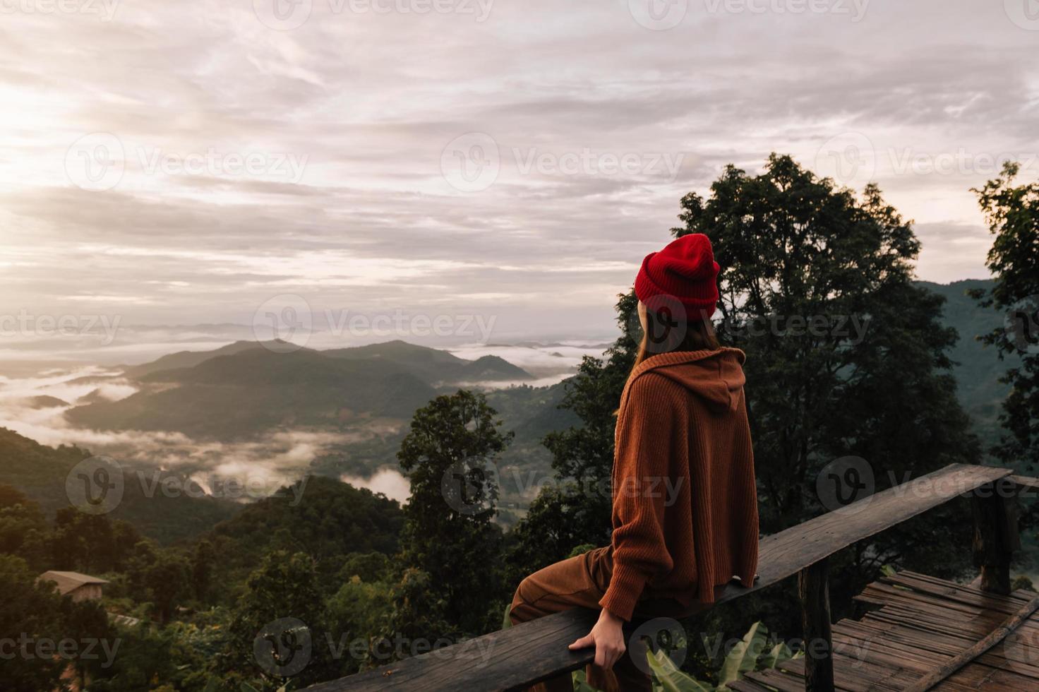 imagen de la vista trasera de una viajera sentada y mirando una hermosa montaña, campo del cielo y vista de la naturaleza a la luz del sol foto